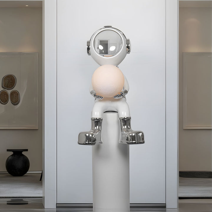 Sculptural astronaut floor lamp holding a round light, perfect for modern decor and artistic illumination.