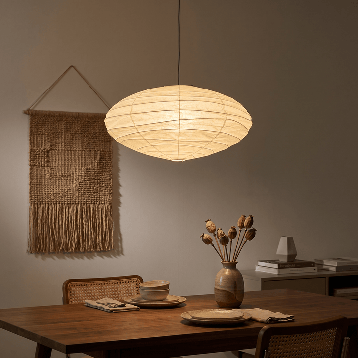 Black cord washi paper pendant light glowing over a warm dining table.