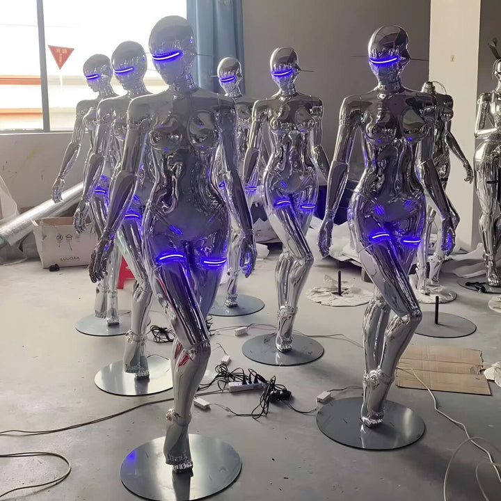Row of modern mannequins with metallic finishes and blue LED accents in a display setup.