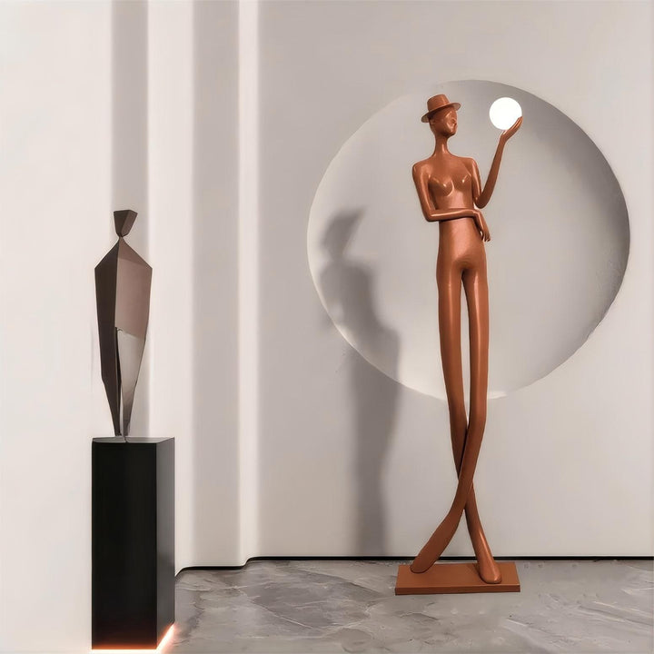 Sculptural floor lamp in art deco style, featuring a tall figure holding a light, perfect for modern living room decor.