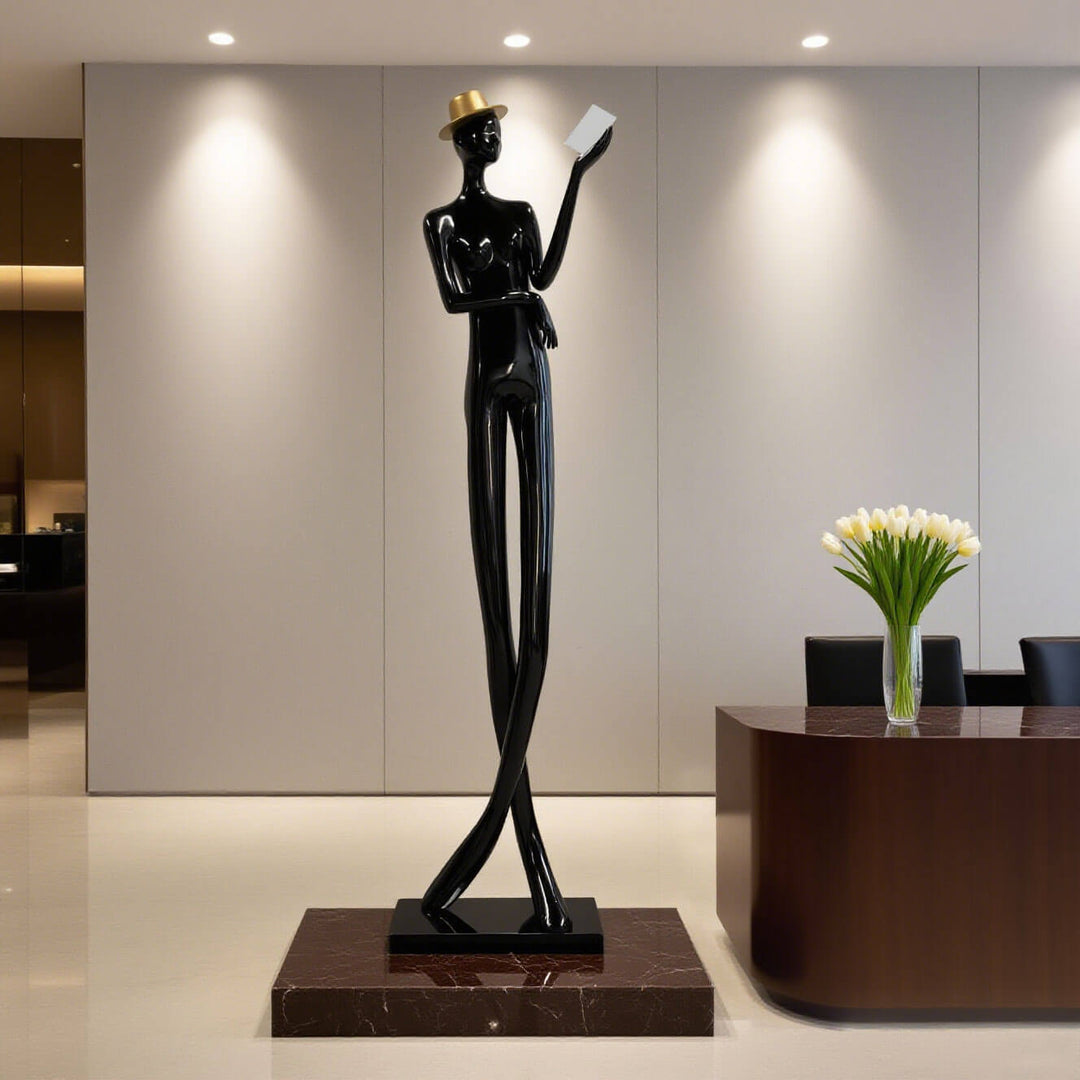 Sculptural floor lamp in art deco style featuring a tall, slender figure holding a book, perfect for living room decor.