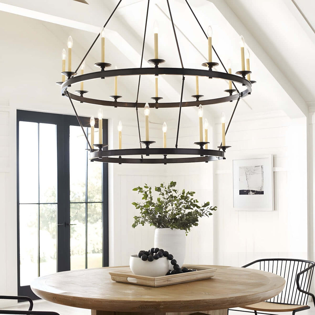 Luvo Serin Chandelier in modern dining room with round table, featuring black and gold finishes and elegant candle-like bulbs.