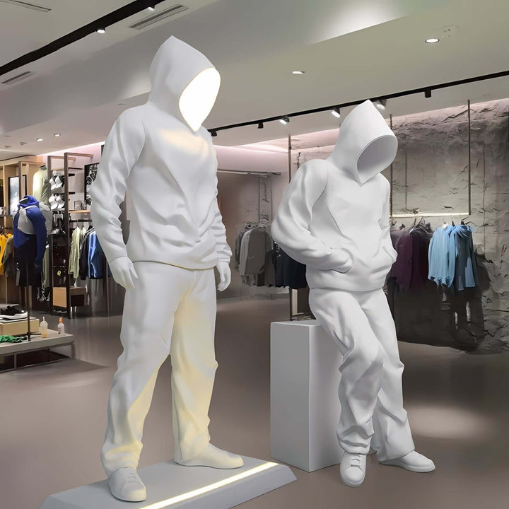 Sculptural display featuring white hooded figures in a modern retail space, highlighting contemporary fashion.