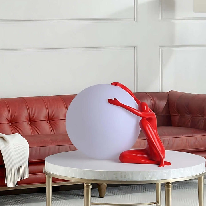 Zelvora sculptural table lamp with red figure holding a glowing sphere, perfect art deco addition to living room decor.