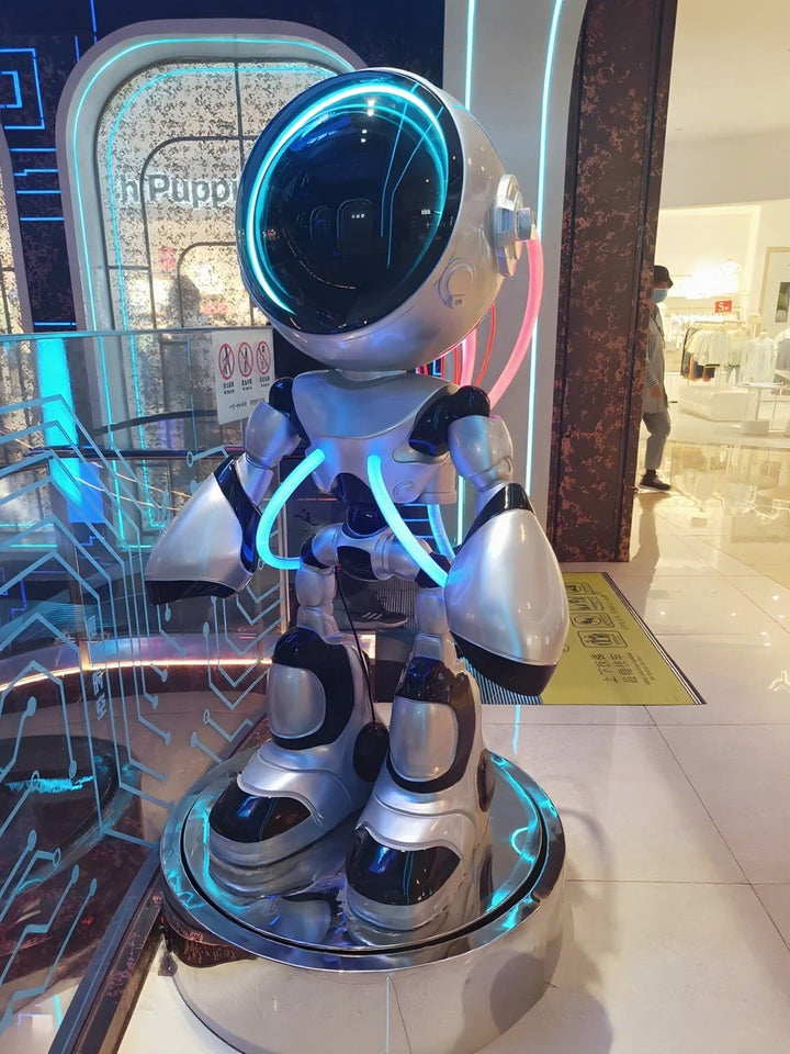 Futuristic robot statue with LED lights in a modern shopping mall setting.