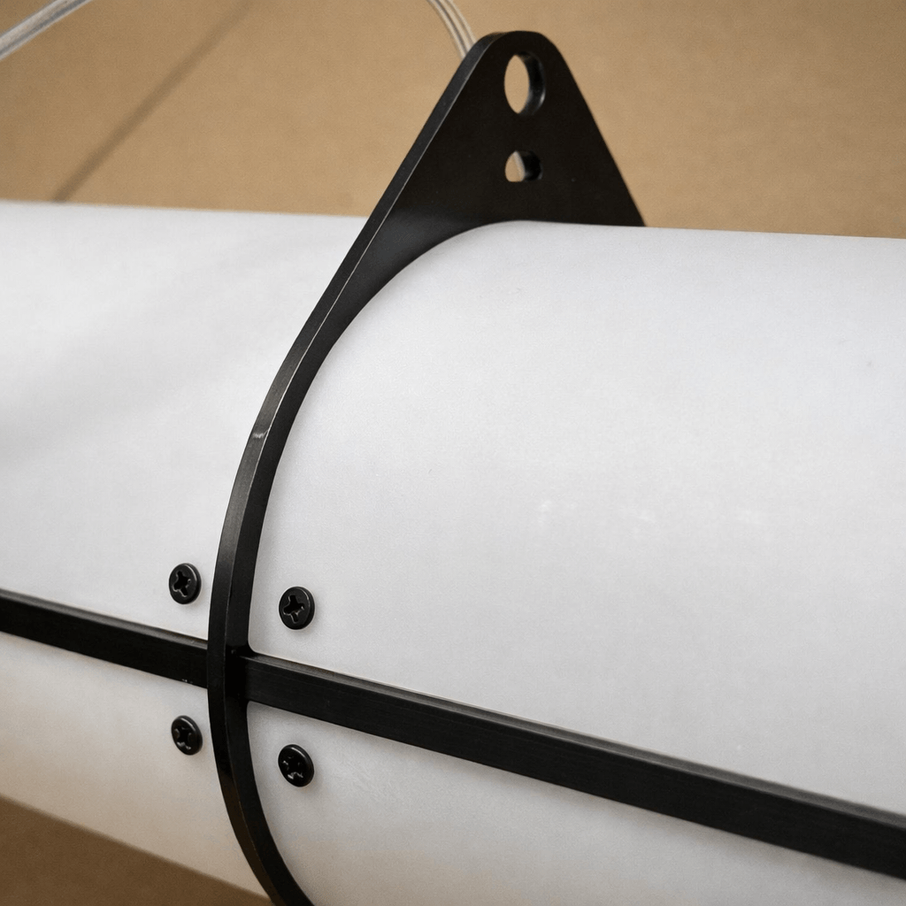 Close-up of the black metal suspension bracket and fastening screws on the frosted acrylic diffuser