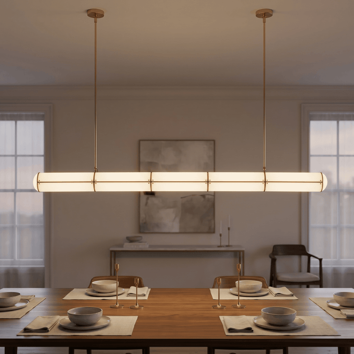 Front view of the brass Acrylic Endless pendant light illuminating a formally set wood dining table