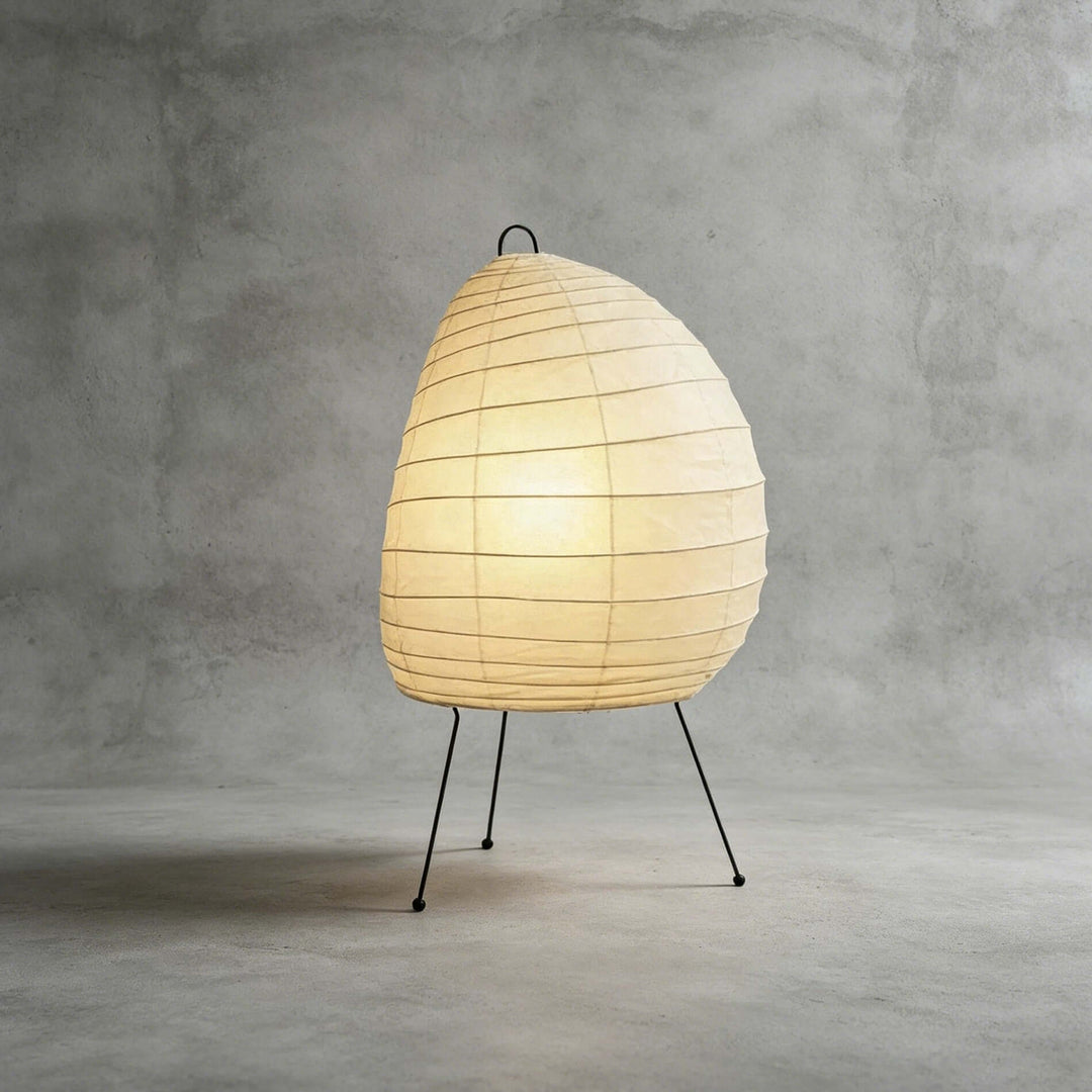 Glowing Akari 1N rice paper table lamp against a textured gray studio background