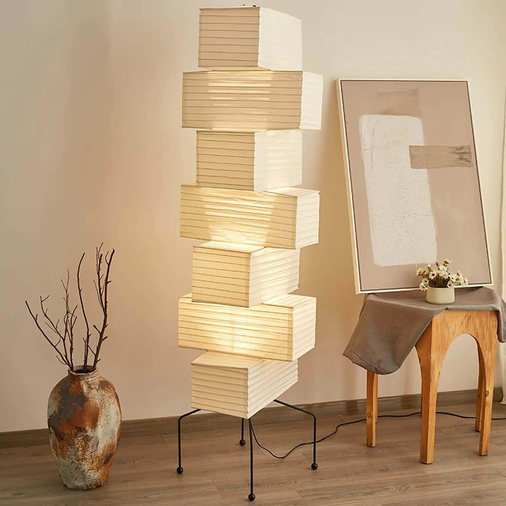 Illuminated Akari UF4-L10 floor lamp styled with a ceramic vase, wood stool and leaning abstract artwork