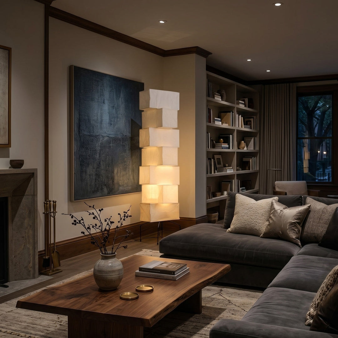 Glowing rice paper floor lamp between a fireplace and built-in bookshelf in a sophisticated living room