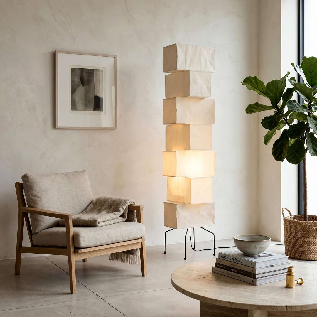 Akari UF4-L10 floor lamp beside a wood lounge chair and leafy plant in a bright neutral reading corner