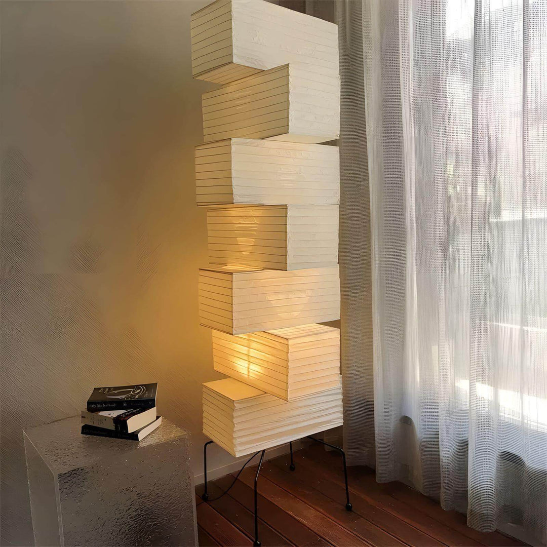 Akari rice paper floor lamp beside sheer window curtains and a textured stone side table