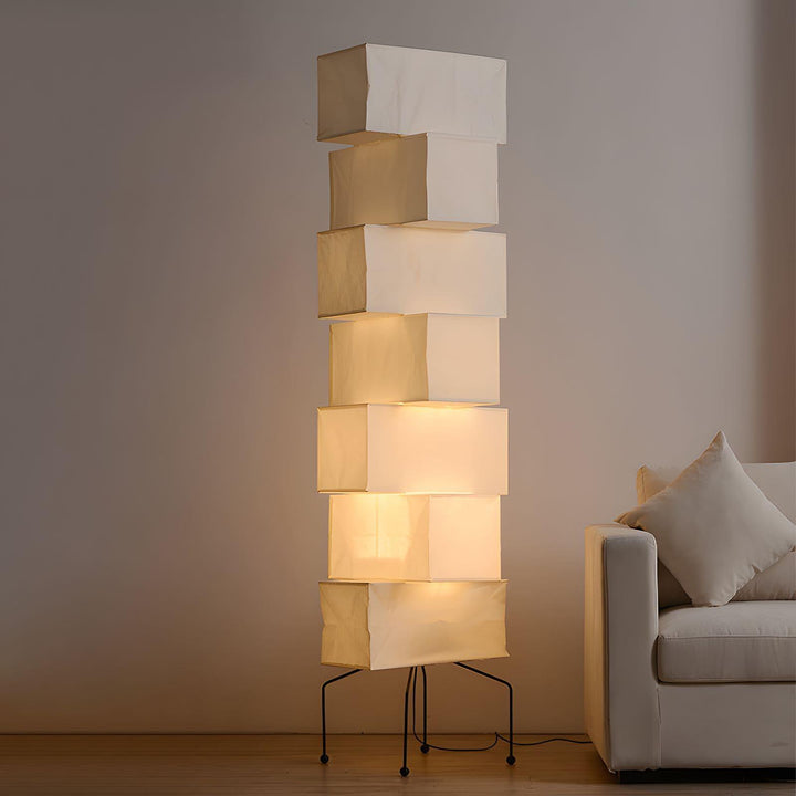 Tall Akari floor lamp with stacked smooth paper lantern shades glowing beside a white sofa