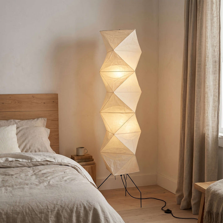 Akari UF4-L8 floor lamp glowing beside a wood bed in a warm neutral bedroom