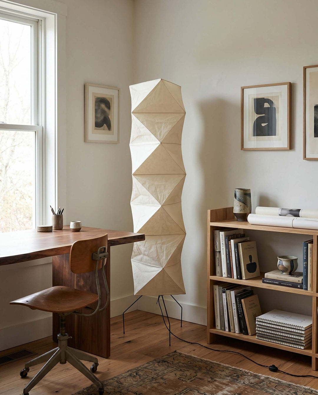 Unlit Akari UF4-L8 floor lamp beside a desk, bookcase, and framed art in a daylight home office