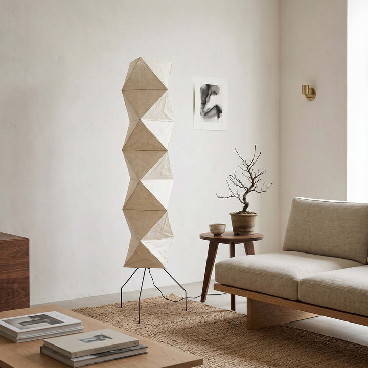 Unlit Akari UF4-L8 floor lamp beside a beige sofa and bonsai table in a minimalist living room