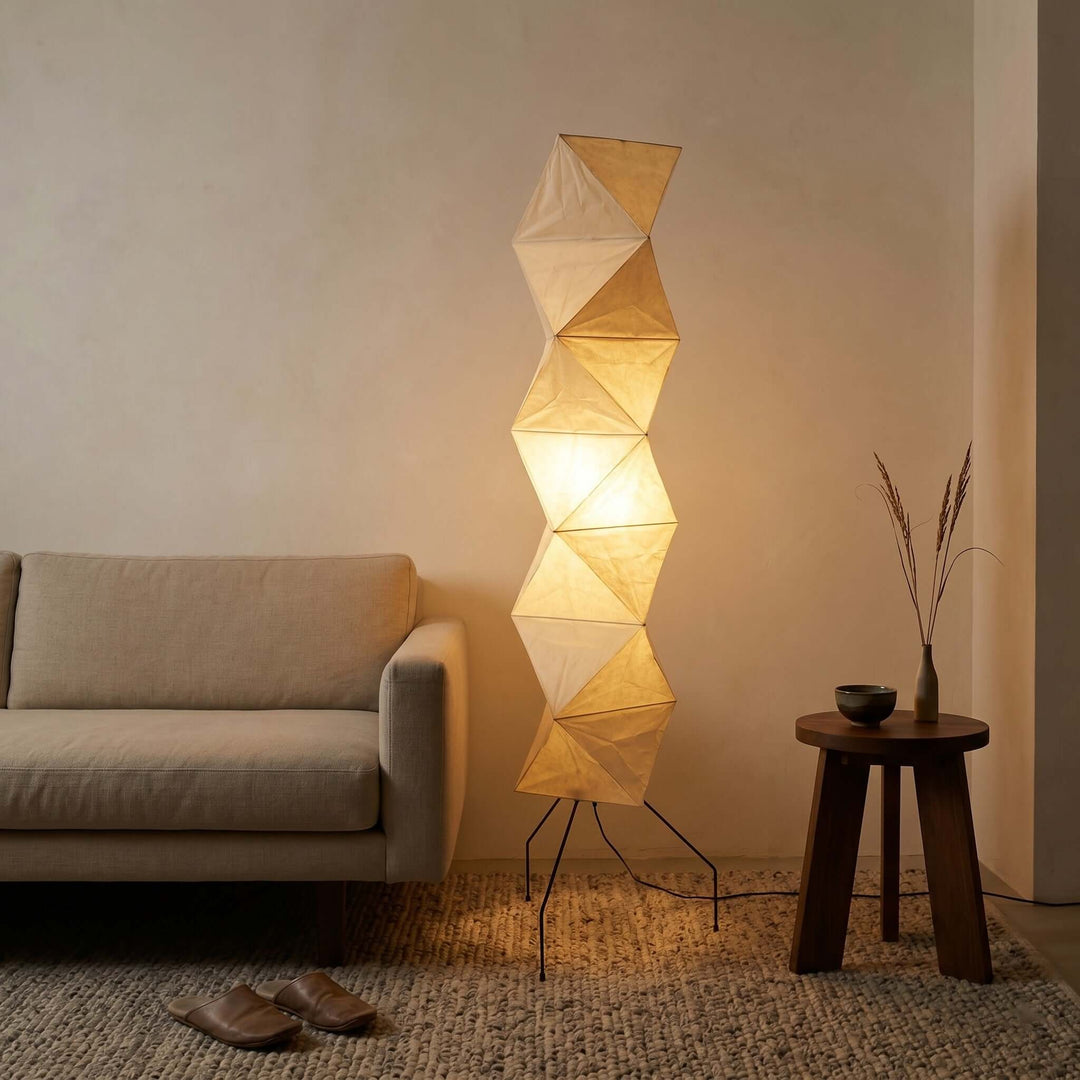Glowing Akari UF4-L8 floor lamp beside a linen sofa and dark wood table in a cozy living room