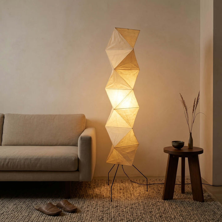 Glowing Akari UF4-L8 floor lamp beside a linen sofa and dark wood table in a cozy living room