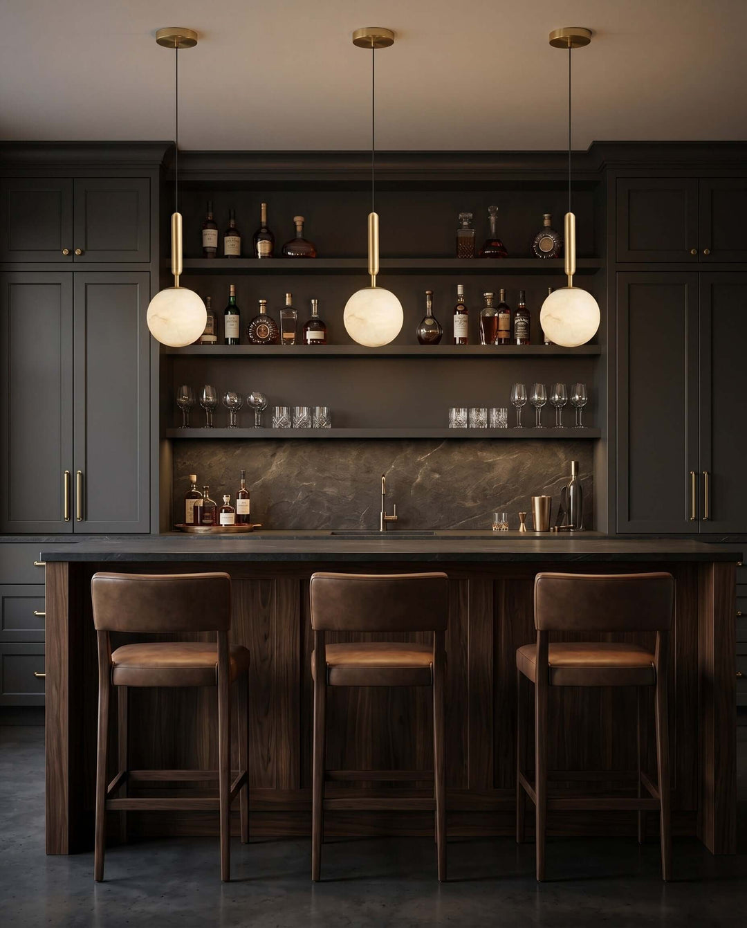 Three glowing alabaster pendant lights above a dark wood home bar with brass details