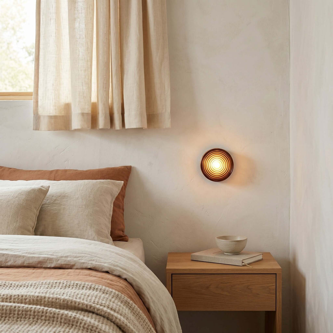 Amber glass Dimple wall sconce beside a bedroom nightstand.