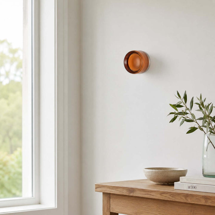 Amber glass Dimple wall sconce near a window and wood console.
