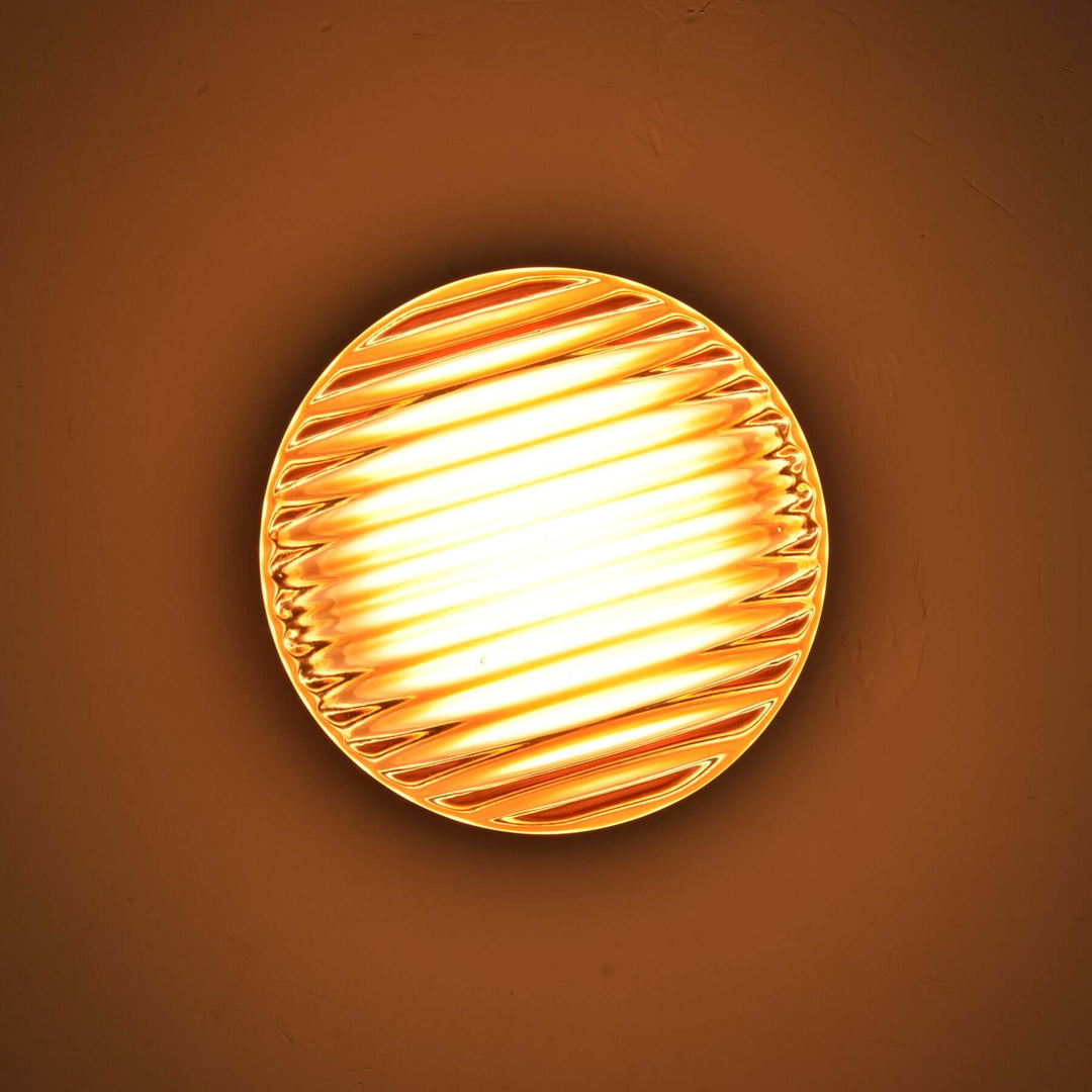 Close-up of an amber ribbed Dimple wall sconce with warm light.