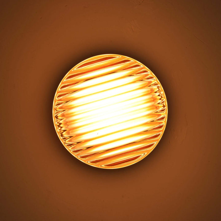 Close-up of an amber ribbed Dimple wall sconce with warm light.