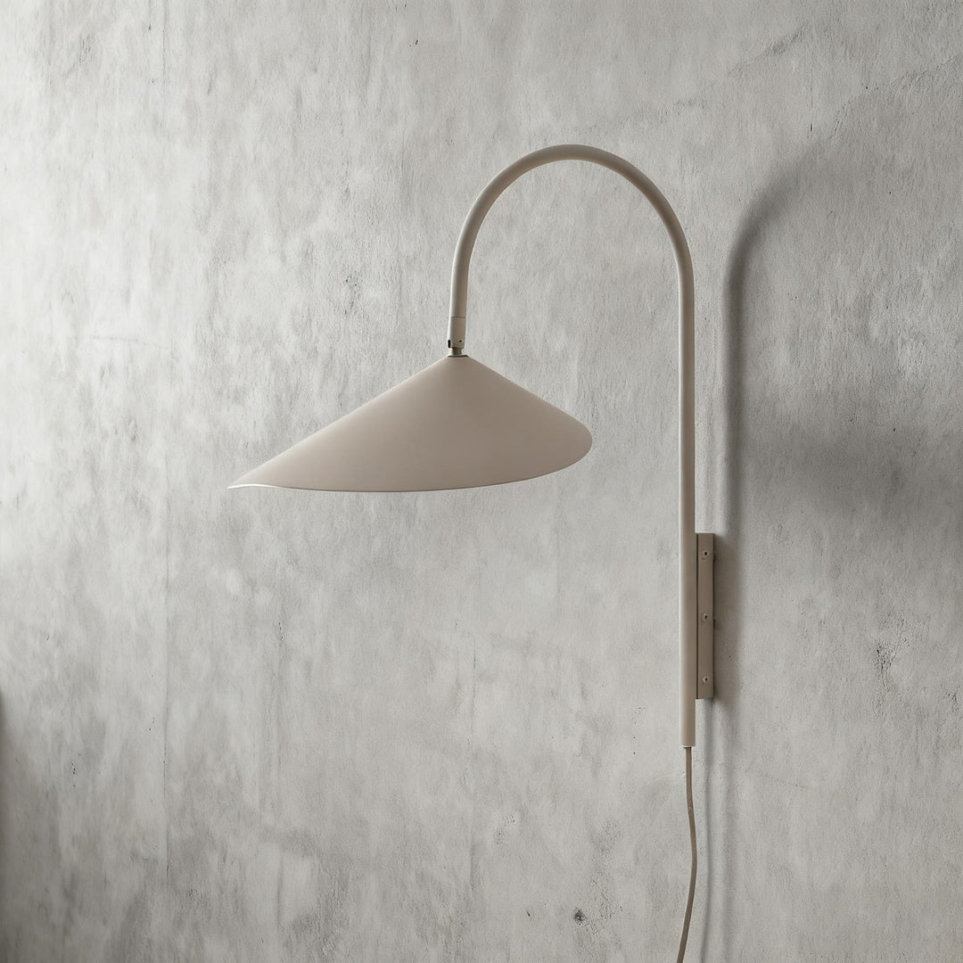 Short beige Arum plug-in wall sconce with a wide metal shade and visible power cord on a plaster wall