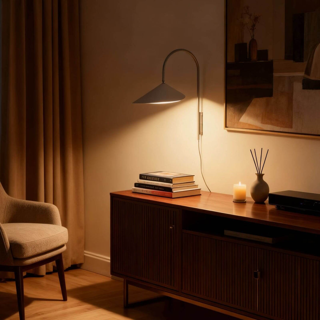 Glowing beige Arum wall sconce above a dark wood console styled with books and a candle