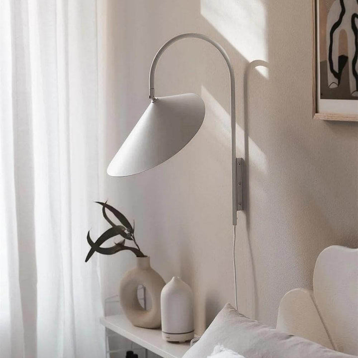 Beige Arum plug-in wall sconce beside decorative ceramic vases in a soft sunlit interior