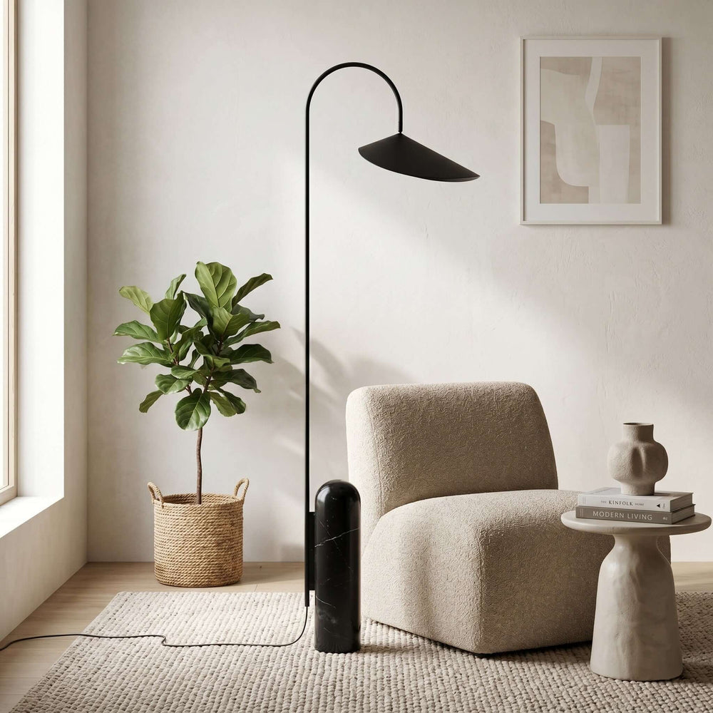 Black Arum living room floor lamp beside a cream lounge chair and potted tree.