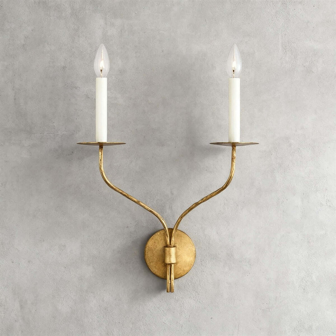 Front view of an aged brass double wall sconce with hand-shaped arms and candle-style bulbs

