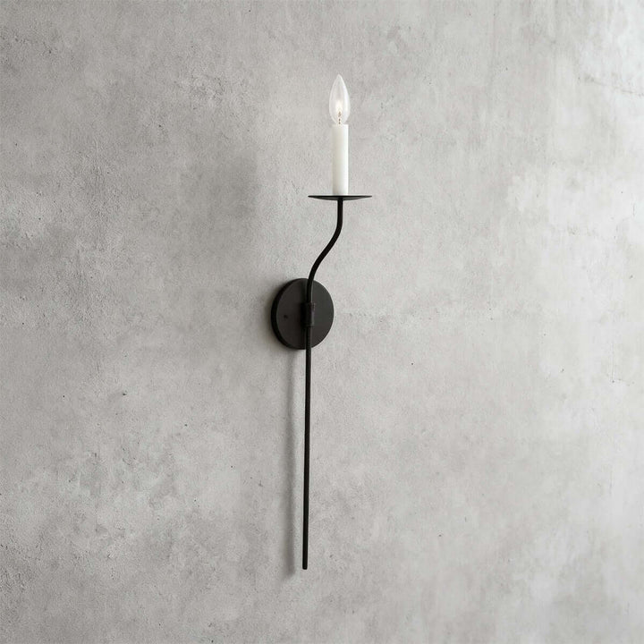 Tall black single-light candle wall sconce with a long vertical stem and minimalist silhouette