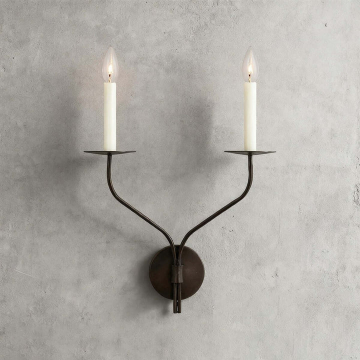 Front view of a black two-light candle wall sconce with curved arms and round wall plate