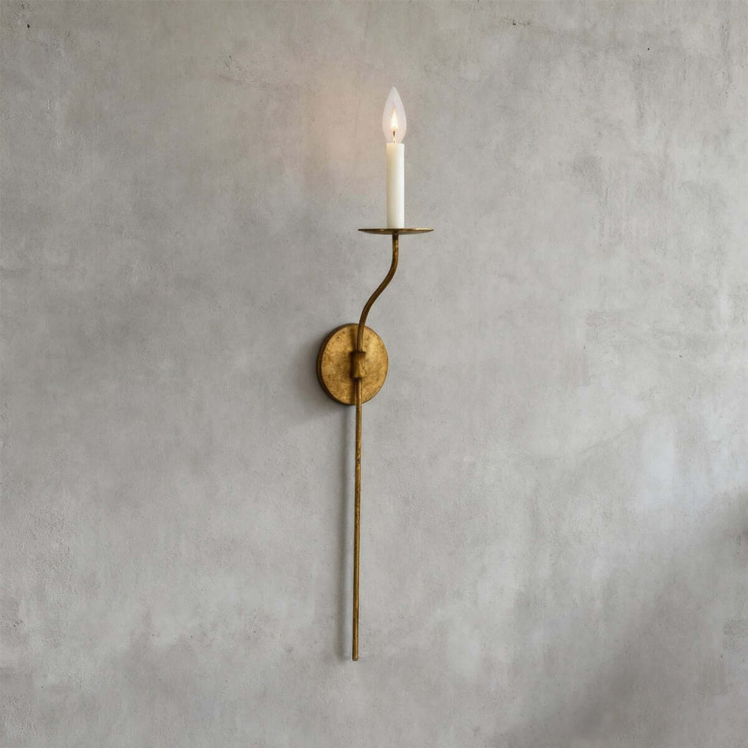 Tall aged brass single-light wall sconce with slender stem and candle-style exposed bulb