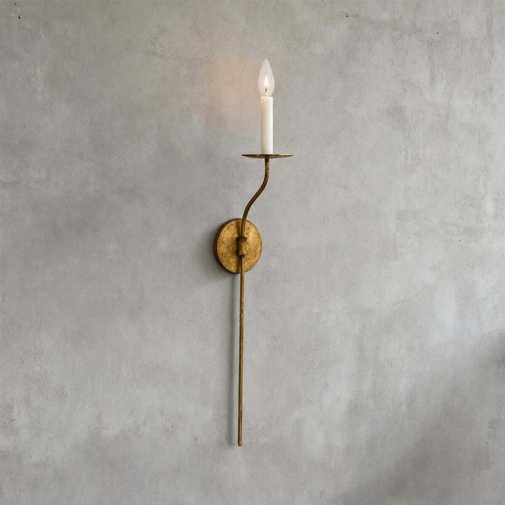 Tall aged brass single-light wall sconce with slender stem and candle-style exposed bulb