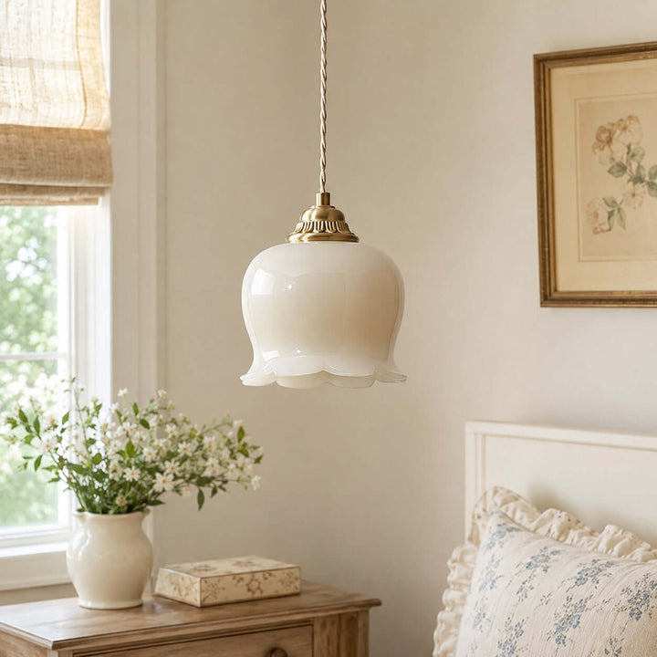 White and brass bedroom pendant light hanging beside a bed in a softly lit vintage interior