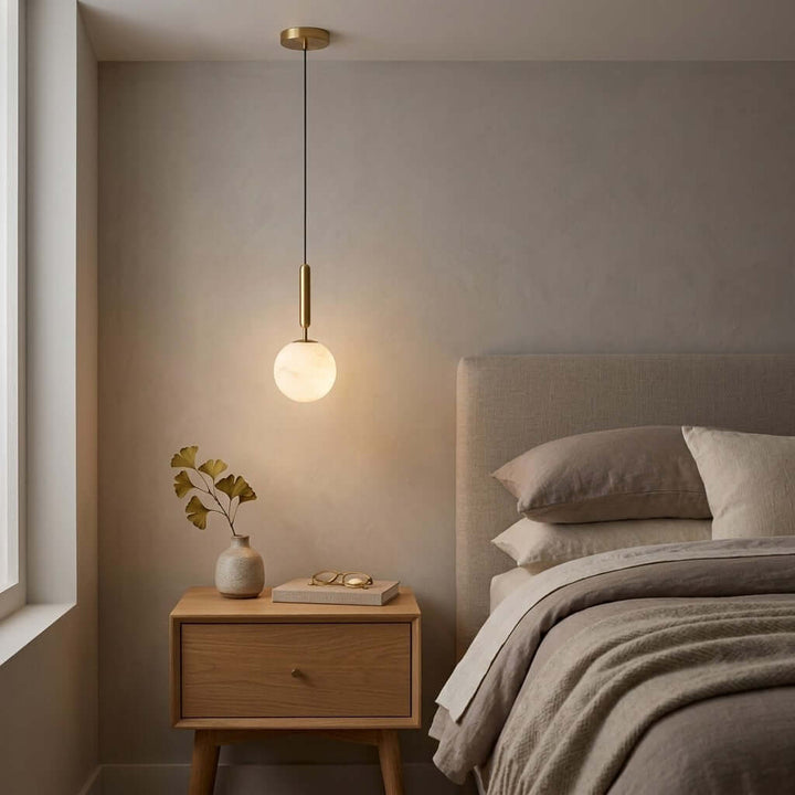Brass and alabaster bedside pendant light casting a warm glow beside a modern bedroom nightstand