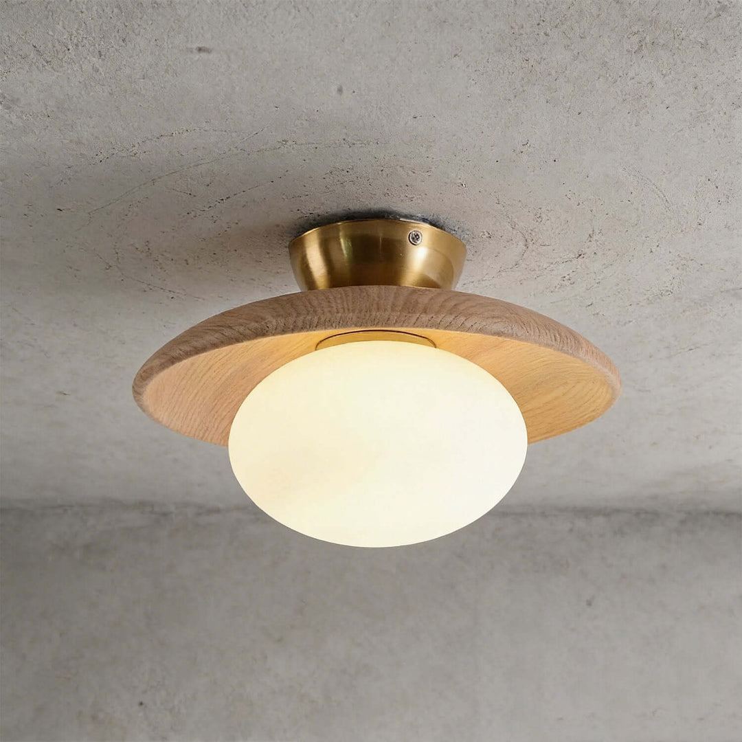 Beige wood flush mount ceiling light with an illuminated frosted glass globe