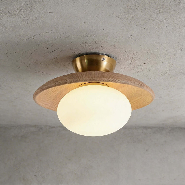 Beige wood flush mount ceiling light with an illuminated frosted glass globe