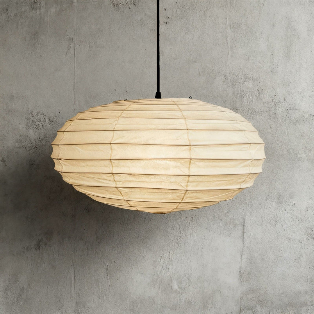 Black cord washi paper pendant light shown close against a gray wall.