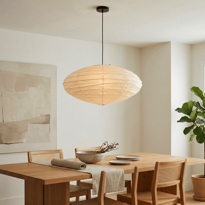 Black cord washi paper pendant light over a wood dining table.