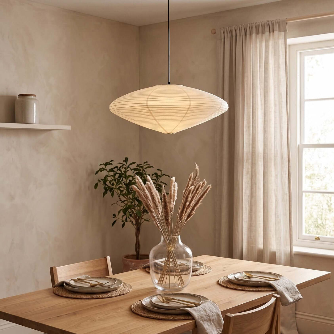 Washi paper pendant light with a black cord over a styled dining table.
