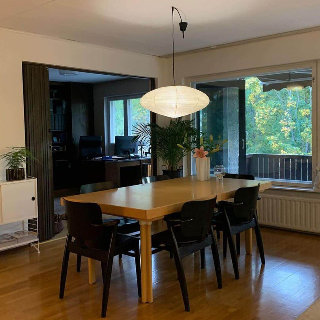 Black cord washi paper pendant light over a dining table.