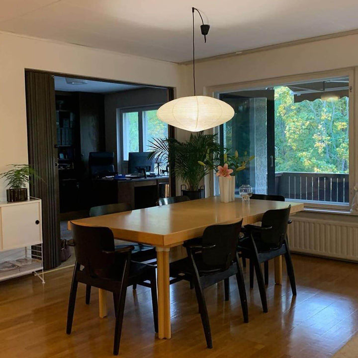 Black cord washi paper pendant light over a dining table.