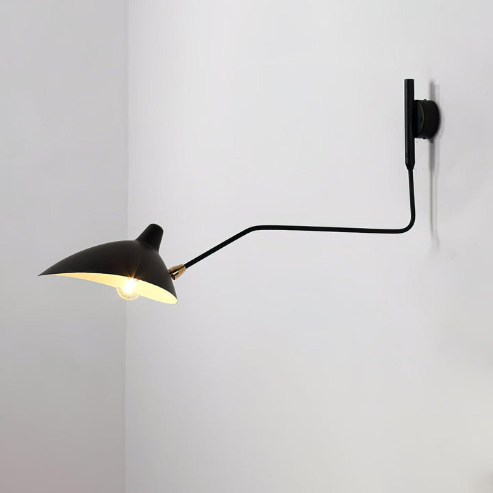 Black single-head swing arm wall lamp with a brass shade joint on a white wall