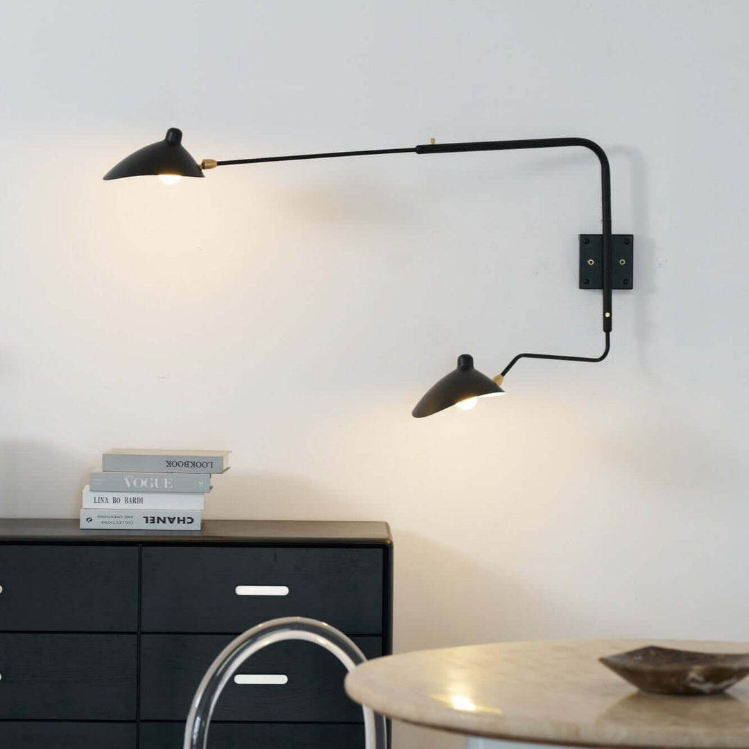 Black two-light swing arm wall sconce illuminating a modern dining area