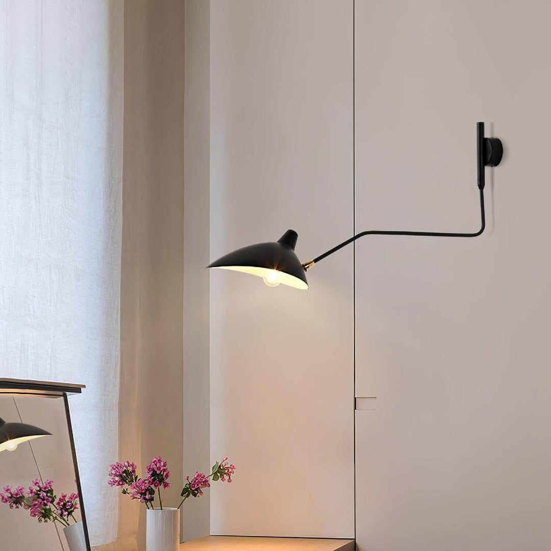 Black swing arm wall light beside a full-length mirror in a minimalist entryway