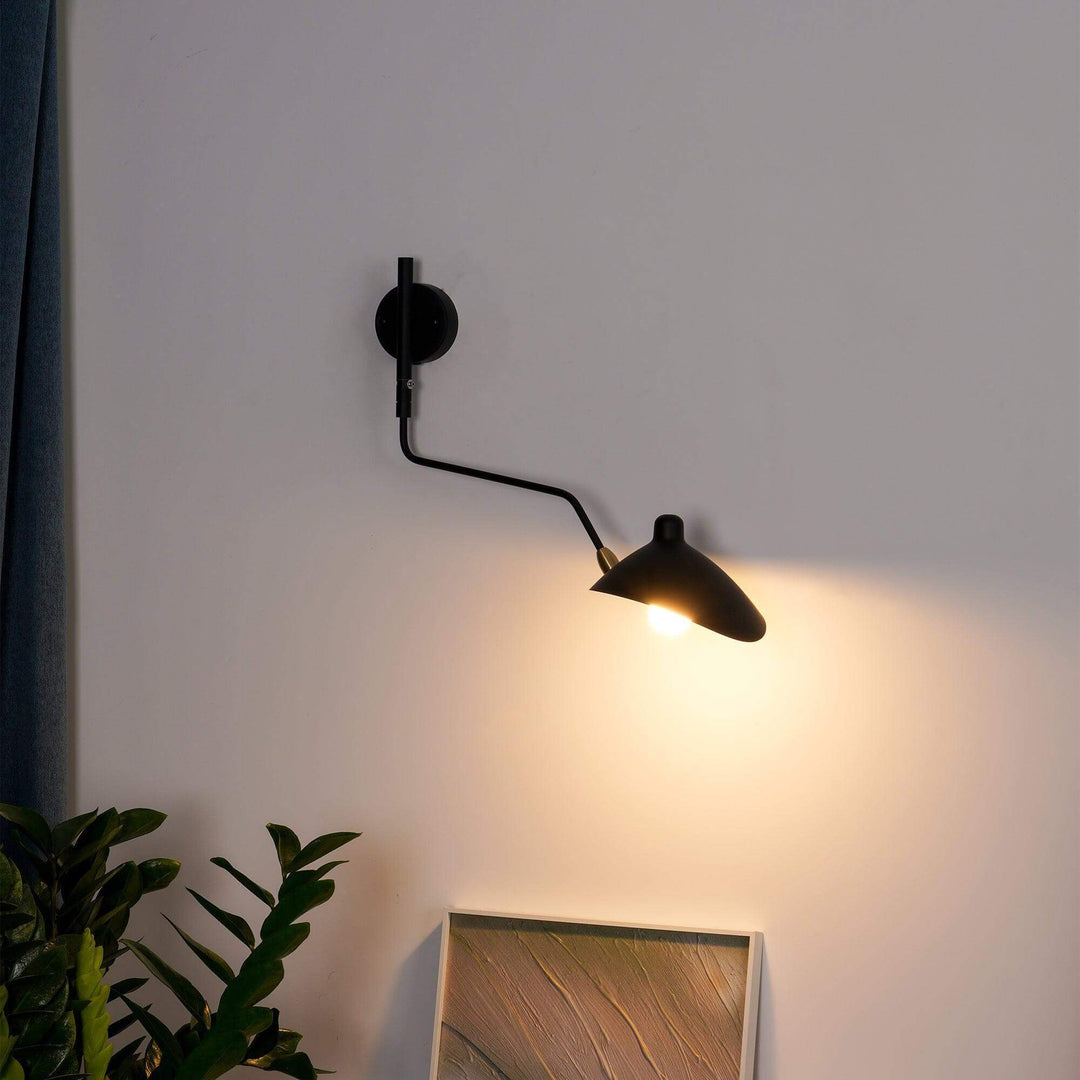 Black adjustable wall sconce casting warm directional light beside indoor plants