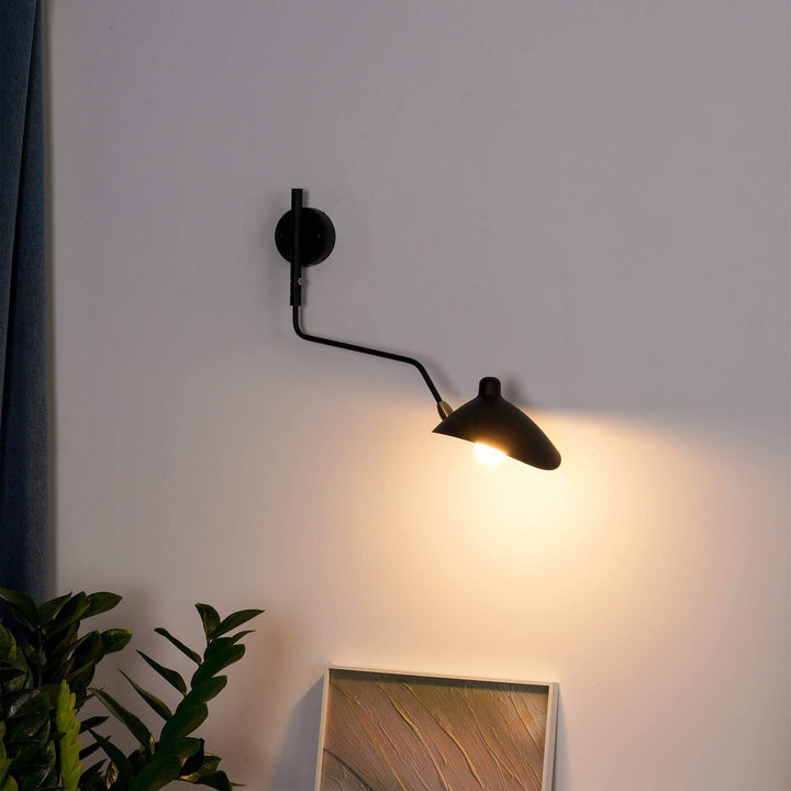 Black adjustable wall sconce casting warm directional light beside indoor plants